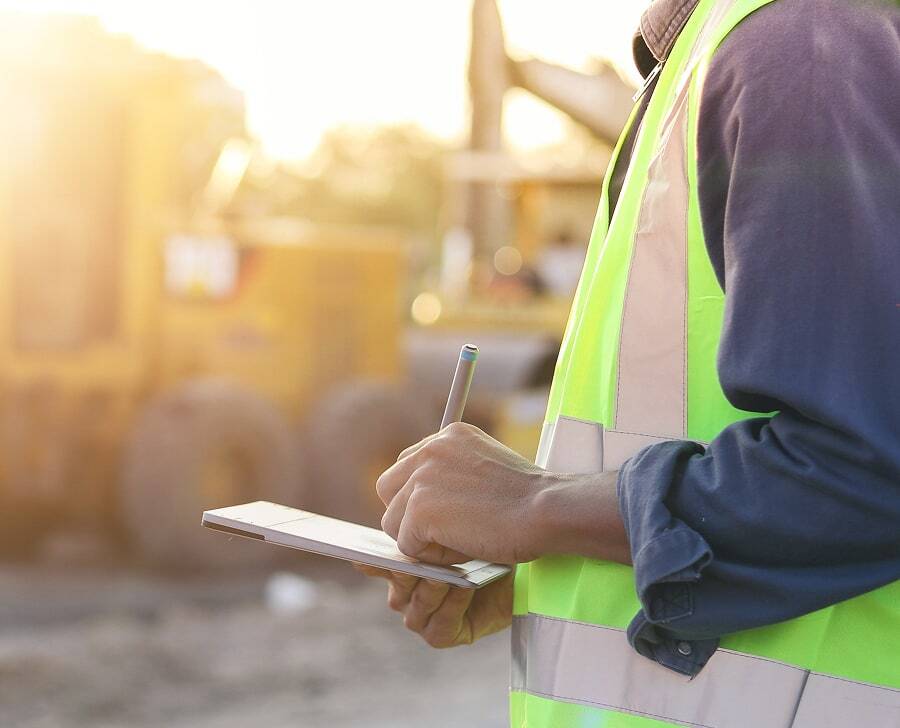 compliance officer in a high-vis vest using a tablet computer